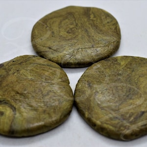 May include: Three round, green and brown, marbled coasters. The coasters are made of a natural material and have a rough texture.