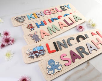 Può includere: Cinque tavole di puzzle in legno con lettere colorate che compongono i nomi Kingsley, Hudson, Amali, Lincoln e Sarah. Ogni tavola presenta un'illustrazione diversa di un animale o di un oggetto.