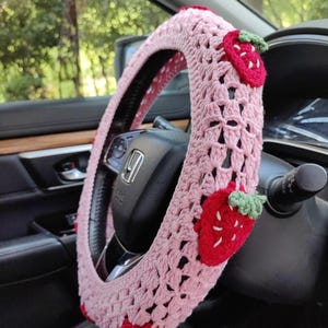 May include: Pink crocheted steering wheel cover with red and green strawberry appliques.