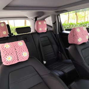 May include: Four pink crocheted headrest covers with white daisy accents for car seats.