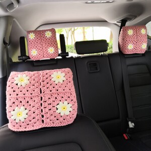 May include: Four pink crocheted headrest covers with white daisy accents for car seats.