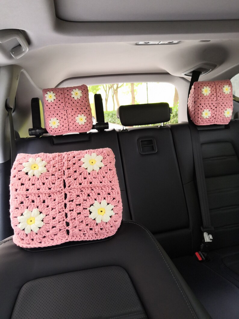 May include: Four pink crocheted headrest covers with white daisy accents for car seats.