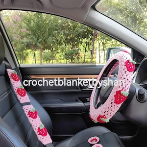 May include: Pink crocheted car seat belt cover and steering wheel cover with strawberry designs. The set also includes two pink crocheted coasters with strawberry designs.