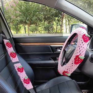 May include: Pink crocheted steering wheel cover and seatbelt covers with strawberry designs.