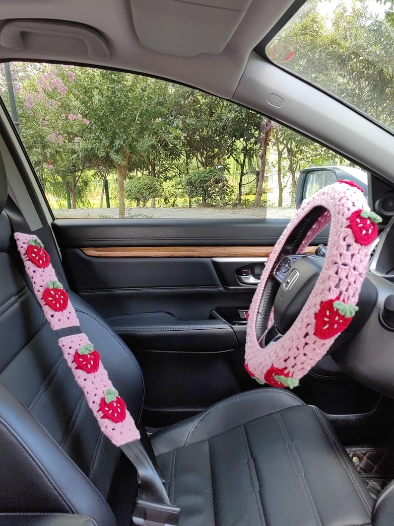 May include: Pink crocheted steering wheel cover and seatbelt covers with strawberry designs.