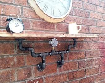 May include: A rustic wooden shelf with black pipe brackets and a pressure gauge. The shelf is mounted on a brick wall and has a clock and a white pitcher on top.