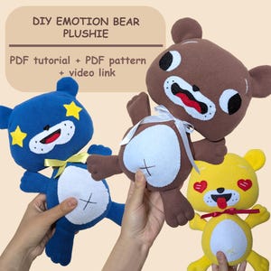 May include: Three handmade plush bears in blue, brown, and yellow. The bears have embroidered faces and are decorated with stars, hearts, and bows. Text at the top reads "DIY EMOTION BEAR PLUSHIE".
