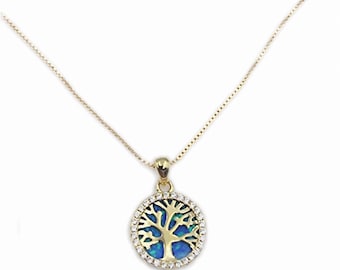 Op de afbeelding: Een gouden ketting met een ronde hanger met een levensboomontwerp met blauwe opaal-inleg en een halo van heldere kristallen.