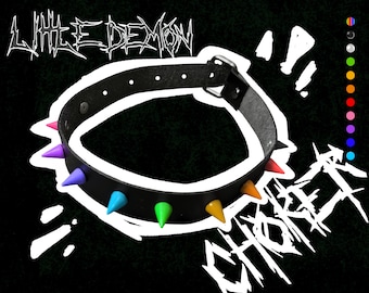 May include: A black leather choker with rainbow colored spikes. The text "LITTLE DEMON" and "CHOKER" are written in a gothic font.