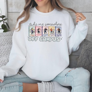 May include: White crew neck sweatshirt with the text "take me somewhere off campus." The graphic features book covers with illustrations of people. The sweatshirt is a casual style.