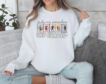 May include: White sweatshirt with the text "take me somewhere off campus." The graphic features book covers with illustrations of people. The sweatshirt is a crew neck style.