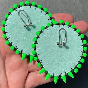 May include: A handmade wooden sign with the text "Welcome" in a playful font. The sign is painted white with a distressed finish, and features a decorative floral design in shades of pink and green. It measures approximately 12 inches wide.