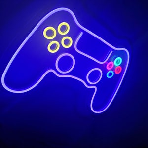 May include: A white neon sign shaped like a video game controller with yellow, pink, blue, and green buttons.