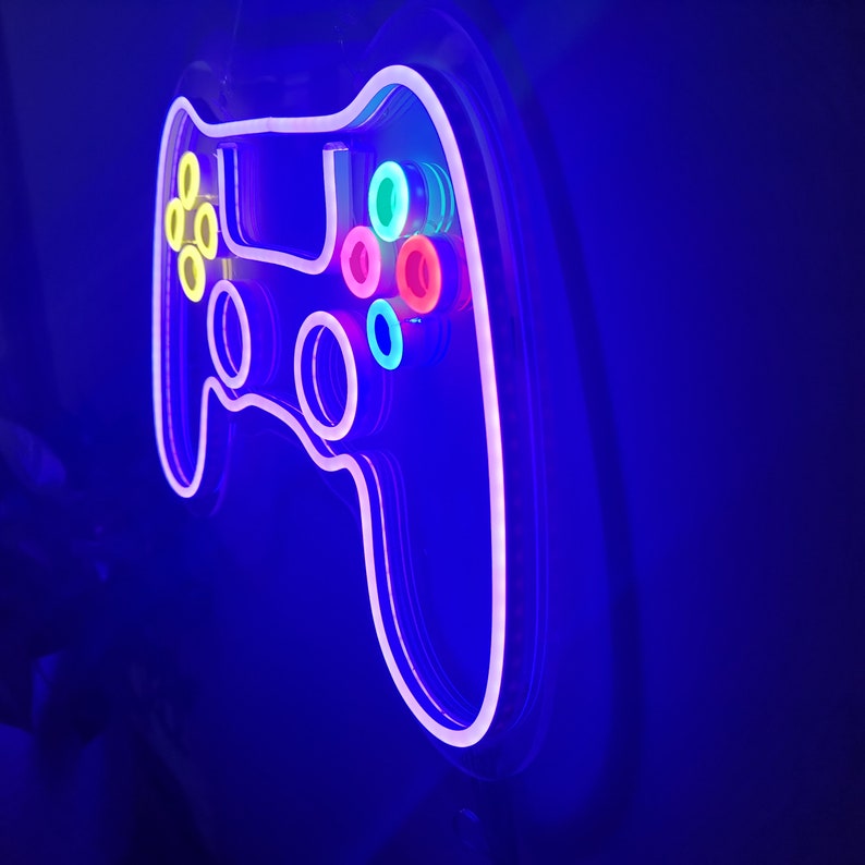 May include: A neon sign shaped like a video game controller with colorful buttons. The sign is lit up in a bright blue color.