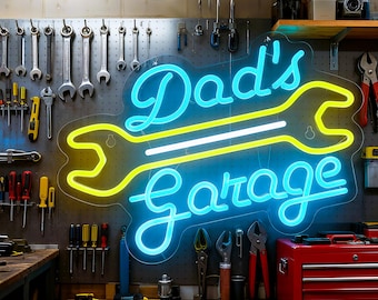 May include: A neon sign in a garage setting, featuring the words "Dad's Garage" in blue script, with a yellow wrench design. Various tools hang on the pegboard wall behind the sign, including wrenches, screwdrivers, and pliers. A red toolbox sits on the right.