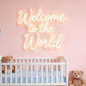 May include: A baby nursery with a white crib, teddy bears, and a "Welcome to the World" neon sign on a pink wall. Decorative stickers of stars and a crescent moon are also on the wall. The crib has a blue sheet.