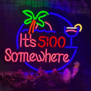 May include: Neon sign with a blue, red and pink colour scheme. It says "It's 5:00 Somewhere" with a palm tree and a cocktail glass.