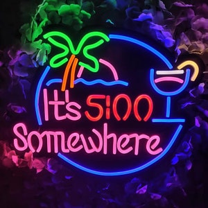 May include: Neon sign with a blue, pink and orange colour scheme. It says "It's 5:00 Somewhere" with a palm tree and a cocktail glass graphic.