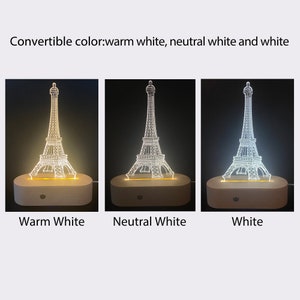 Puede incluir: Una base de madera con una luz nocturna de dise&ntilde;o de Torre Eiffel blanca. La luz tiene tres opciones de color: blanco c&aacute;lido, blanco neutro y blanco.