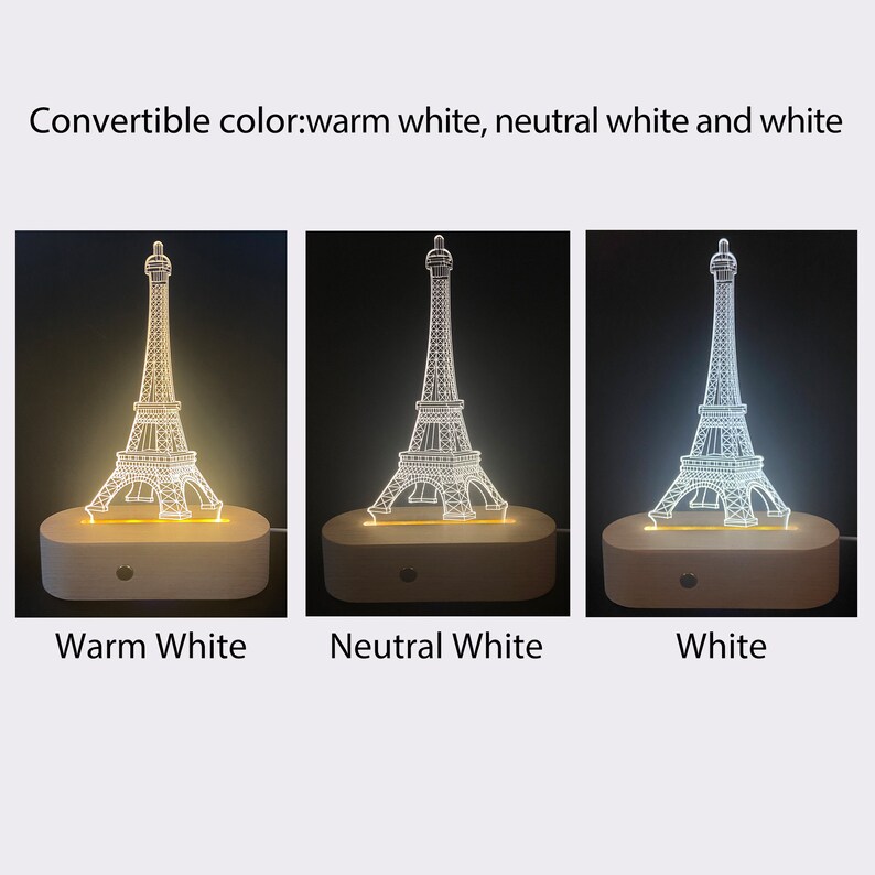 Puede incluir: Una base de madera con una luz nocturna de dise&ntilde;o de Torre Eiffel blanca. La luz tiene tres opciones de color: blanco c&aacute;lido, blanco neutro y blanco.
