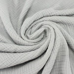 May include: A close-up of a soft, gray, crinkled fabric. The fabric has a waffle-like texture and is made of cotton.
