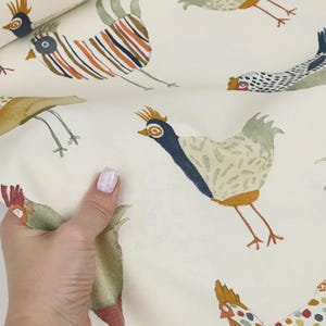 May include: White fabric with a repeating pattern of colorful chickens. The chickens are illustrated in a whimsical style with various colors and patterns.