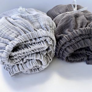 May include: Two rolled up fabric covers, one gray and one light gray. The covers are made of a soft, textured material and have a gathered elastic edge.