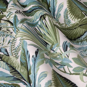 May include: White fabric with a green and blue tropical leaf pattern. The fabric has a soft, textured feel.