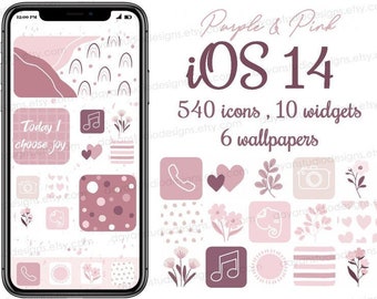 May include: A mockup of an iPhone screen with a pink and white colour scheme. The screen shows a variety of icons and widgets, including a camera, music note, and a heart. The text "iOS 14" is displayed at the top of the screen, along with the text "540 icons, 10 widgets, 6 wallpapers".