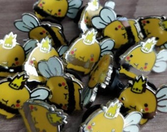 May include: A collection of 12 yellow and black bee pins with a crown on their heads. The pins are made of metal and have a shiny finish.