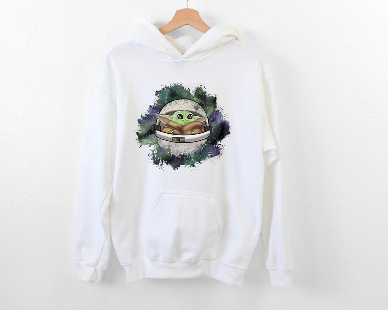 May include: White hooded sweatshirt with a graphic print of a green alien character in a spaceship against a galaxy background.