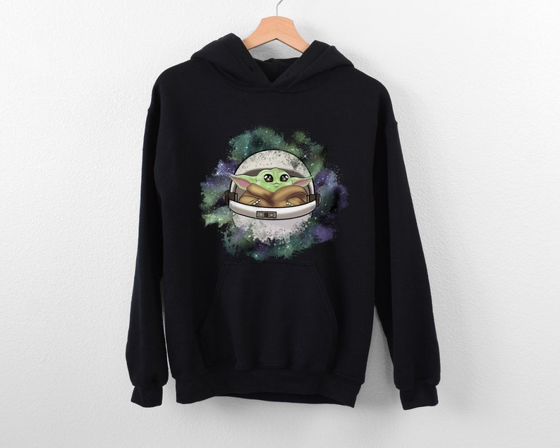 May include: Black hooded sweatshirt with a graphic print of a green alien character in a spaceship against a galaxy background.