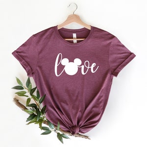 May include: Burgundy t-shirt with a white Mickey Mouse head and the word "love" in a cursive font.