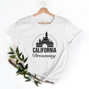 Puede incluir: Camiseta blanca con un gr&aacute;fico negro del castillo de la Bella Durmiente y el texto "CALIFORNIA Dreaming".