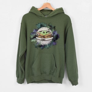 May include: A green hooded sweatshirt with a graphic print of a cartoon character in a spaceship against a galaxy background.