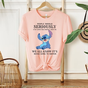 May include: Pink t-shirt with a blue cartoon character and the text "PEOPLE SHOULD SERIOUSLY STOP EXPECTING NORMAL FROM ME WE ALL KNOW IT'S NEVER GOING TO HAPPEN".
