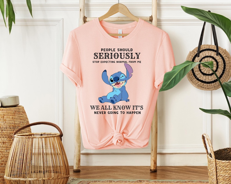 May include: Pink t-shirt with a blue cartoon character and the text "PEOPLE SHOULD SERIOUSLY STOP EXPECTING NORMAL FROM ME WE ALL KNOW IT'S NEVER GOING TO HAPPEN".