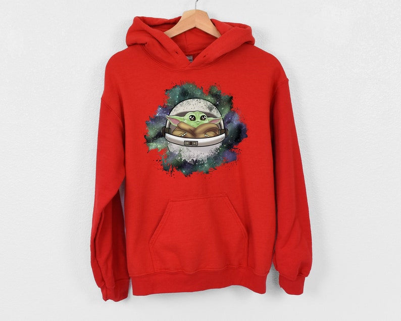 May include: Red hooded sweatshirt with a graphic print of a green alien character in a spaceship against a galaxy background.