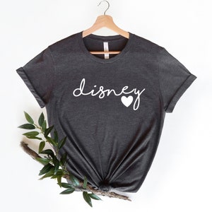 May include: A dark gray t-shirt with the word "disney" written in white cursive with a white heart next to it.