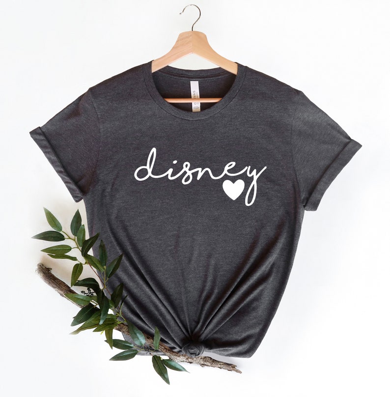 May include: A dark gray t-shirt with the word "disney" written in white cursive with a white heart next to it.