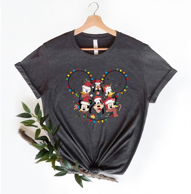 May include: A dark gray t-shirt with a Christmas-themed design featuring Mickey Mouse and his friends. The design shows Mickey Mouse, Minnie Mouse, Donald Duck, Goofy, and Pluto wearing Santa hats and surrounded by colorful Christmas lights in the shape of Mickey Mouse's ears.