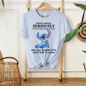 May include: Light blue t-shirt with a cartoon Stitch character from Lilo & Stitch. The text on the shirt reads "People should seriously stop expecting normal from me. We all know it's never going to happen."
