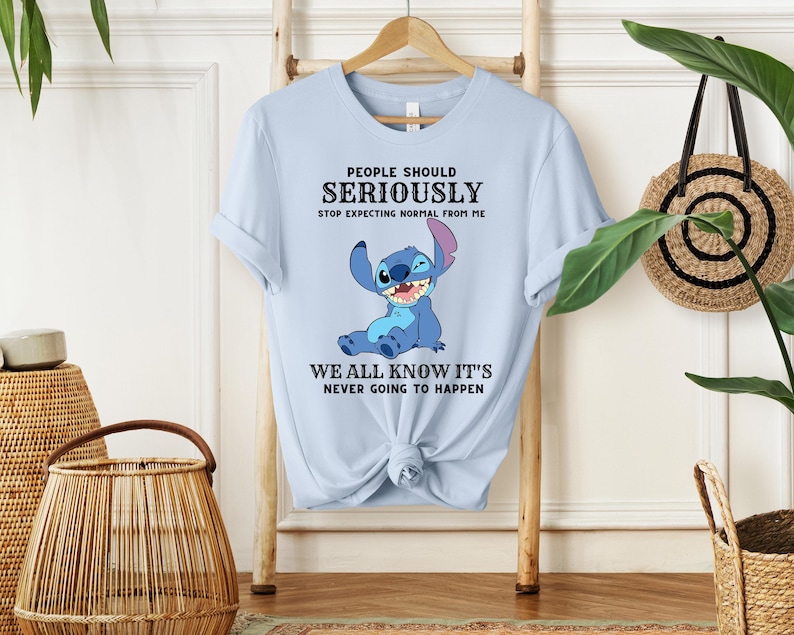 May include: Light blue t-shirt with a cartoon Stitch character from Lilo & Stitch. The text on the shirt reads "People should seriously stop expecting normal from me. We all know it's never going to happen."
