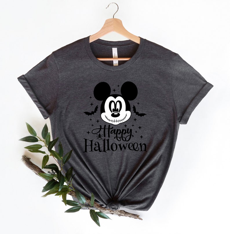 Puede incluir: Una camiseta gris oscuro con un gr&aacute;fico en blanco y negro de Mickey Mouse con una sonrisa cosida y el texto "Happy Halloween".