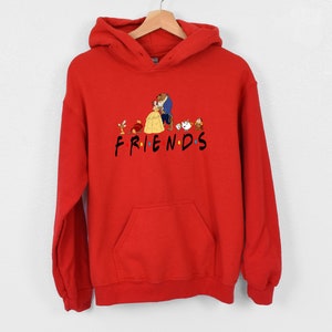 May include: Red hooded sweatshirt with a graphic of Belle and the Beast from Beauty and the Beast, along with other characters from the movie. The text "FRIENDS" is printed below the graphic.