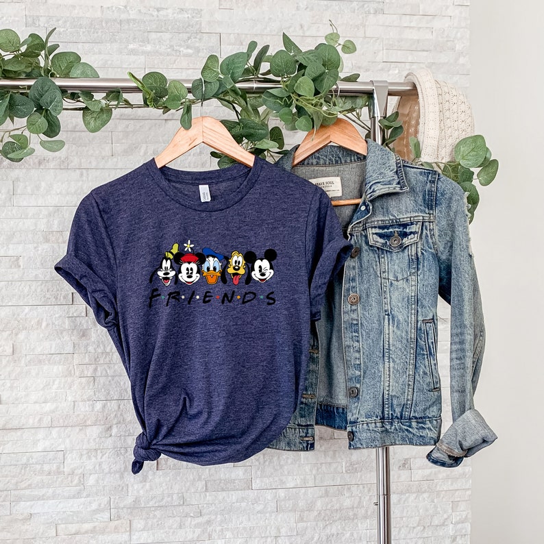 May include: A navy blue t-shirt with a graphic of Mickey Mouse, Donald Duck, Goofy, Pluto, and a cartoon character with a star on their head. The text "FRIENDS" is printed below the characters.