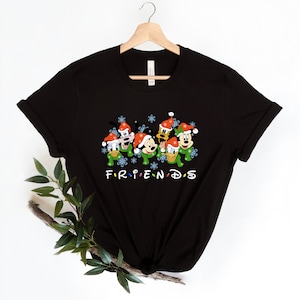 May include: Black t-shirt with a graphic of Mickey Mouse, Donald Duck, Goofy, and Pluto wearing Santa hats and scarves. The text "FRIENDS" is below the characters.