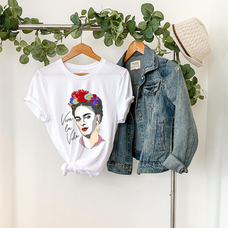 May include: White t-shirt with a colorful illustration of Frida Kahlo wearing a flower crown and the text "Viva la Vida".