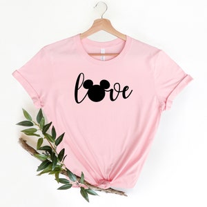 May include: Pink t-shirt with a black Mickey Mouse head and the word "love" in a cursive font.