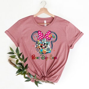 May include: A pink t-shirt with a graphic of Mickey Mouse and friends in a car in front of the Cinderella Castle. The graphic is inside a large Mickey Mouse ear with a pink bow. The text "Best Day Ever" is below the graphic.
